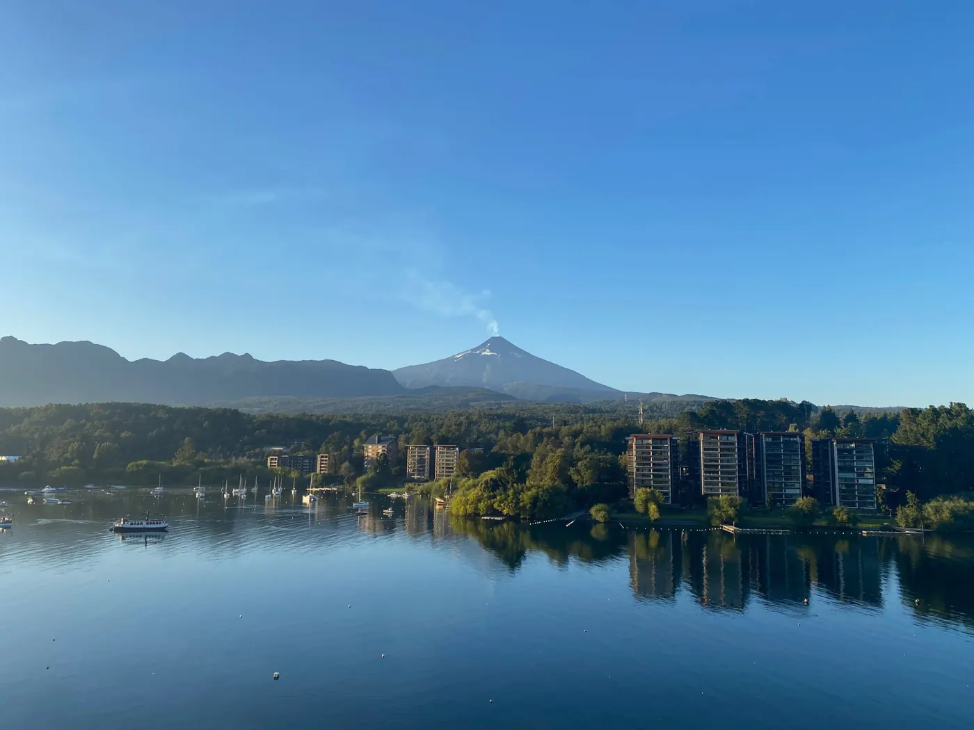 Lago en calma con un volcán humeante al amanecer