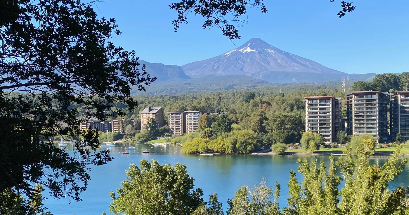 Volcán nevado sobre un lago y la ciudad a su orilla, sur de Chile